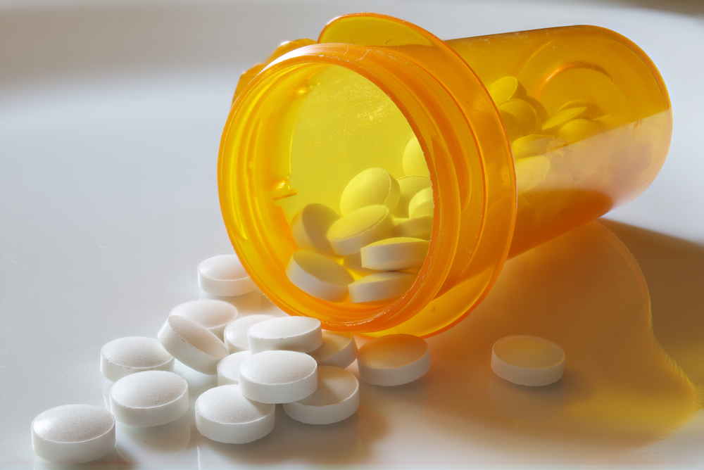 Opioid pills spill out of a prescription medication bottle.