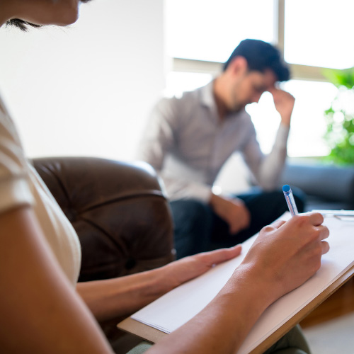 A therapist writes a note while in a session with a client at a drug rehab center.