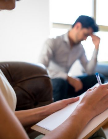 A therapist writes a note while in a session with a client at a drug rehab center.